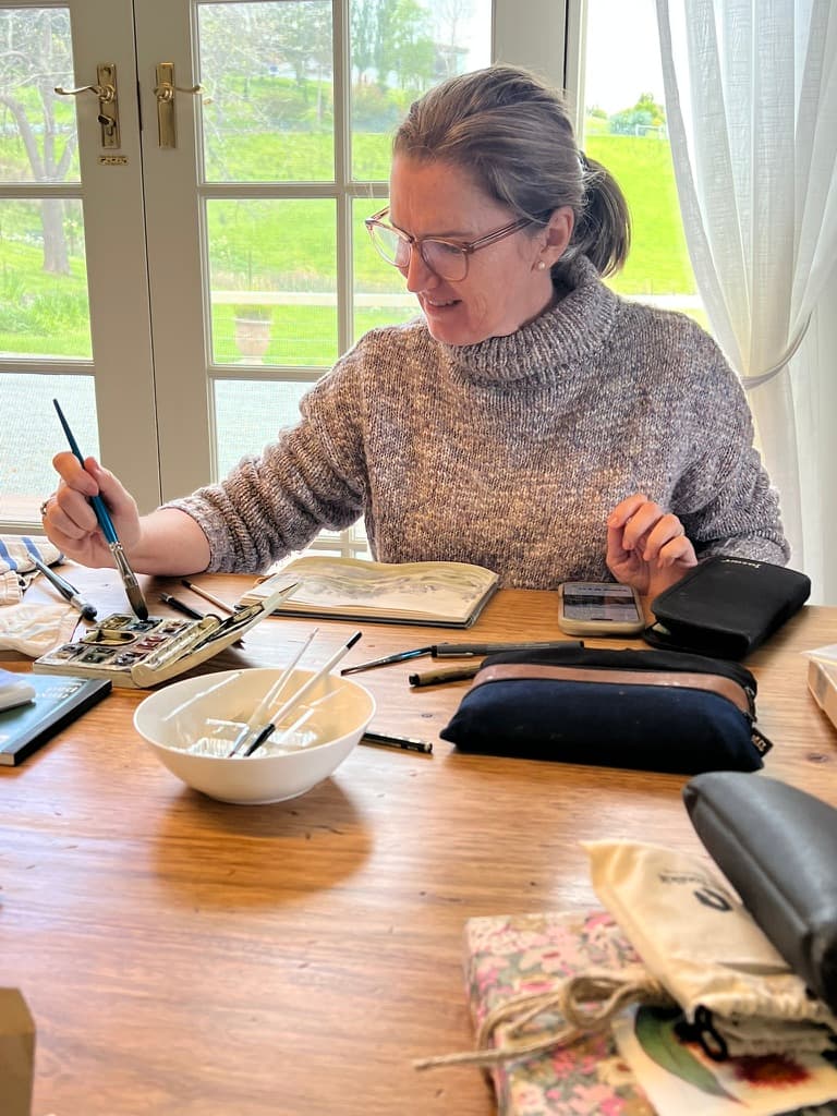 Artist painting watercolours at The Cottage at Flowerpot