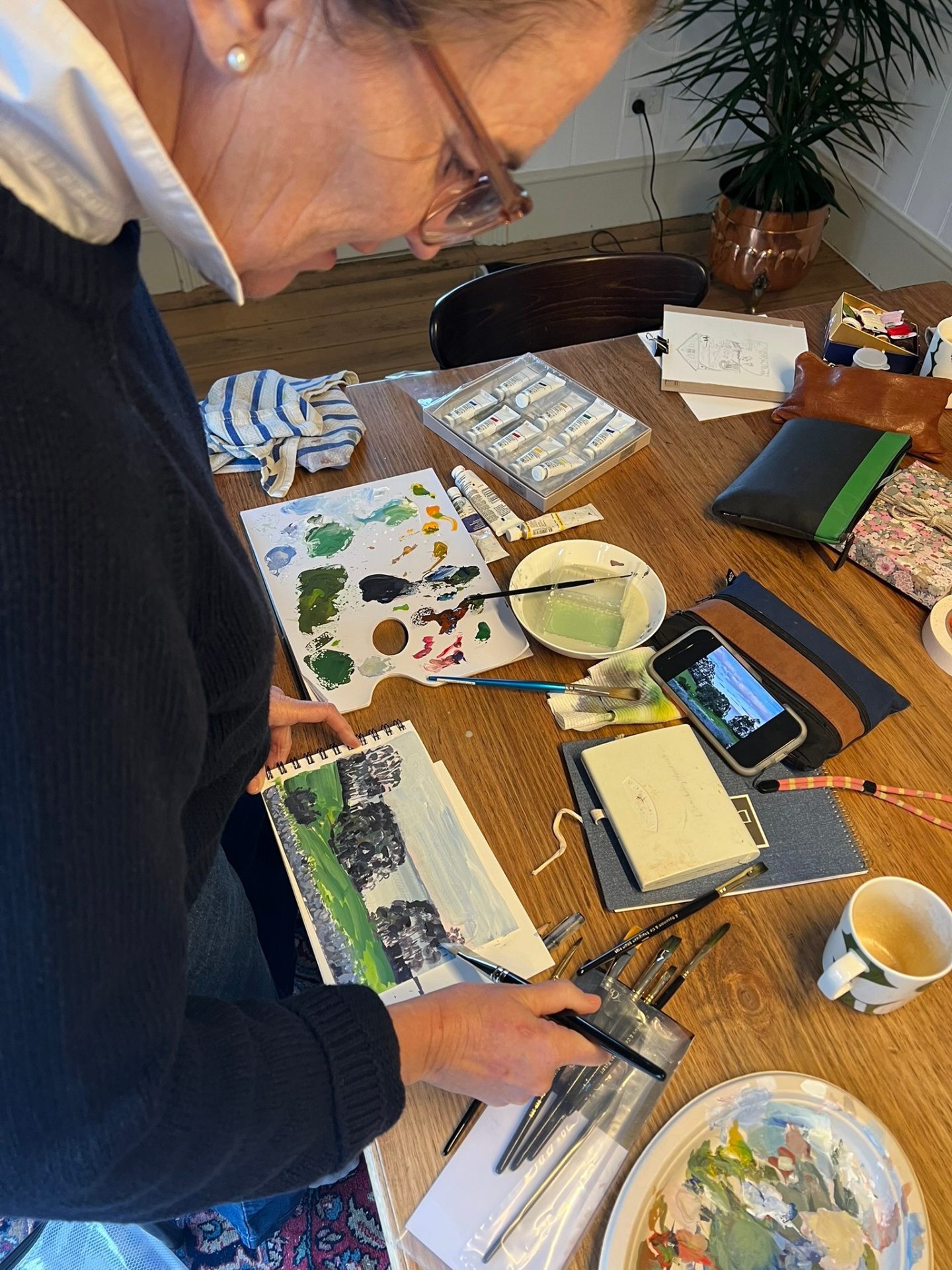 Artist painting a landscape in gouache at The Cottage